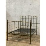 An Edwardian brass and green lacquered double bed frame, with urn finials, sprung base and moving on