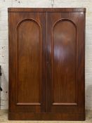 A Victorian mahogany double wardrobe, with two arch panel doors enclosing an interior fitted with