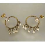 A pair of yellow metal wire woven circular hoop drop earings with cultured pearl set posts and