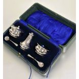 A Birmingham silver three piece condiment set of waisted design complete with original blue glass