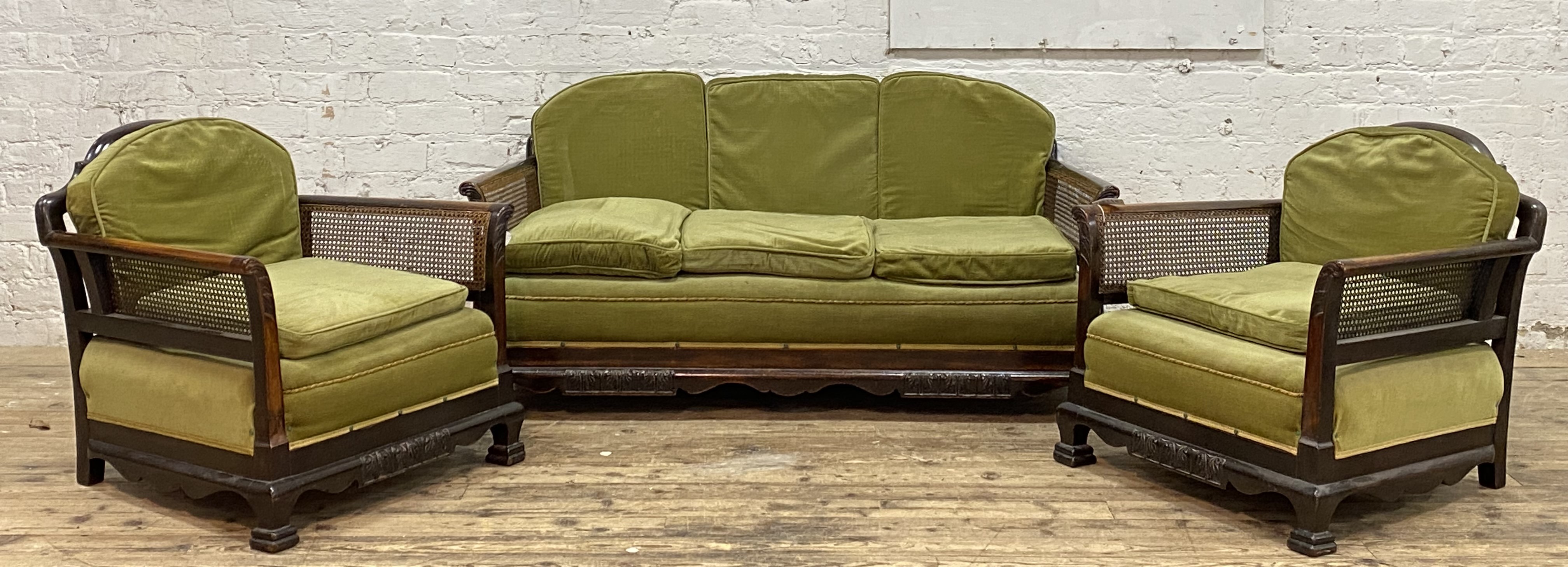 A 1920's walnut three piece bergere suite with single cane panel backs and sides, comprising a three