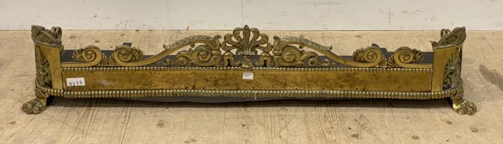 A well cast 19th century brass fire fender, decorated with open scrolls and anthemion motifs, raised