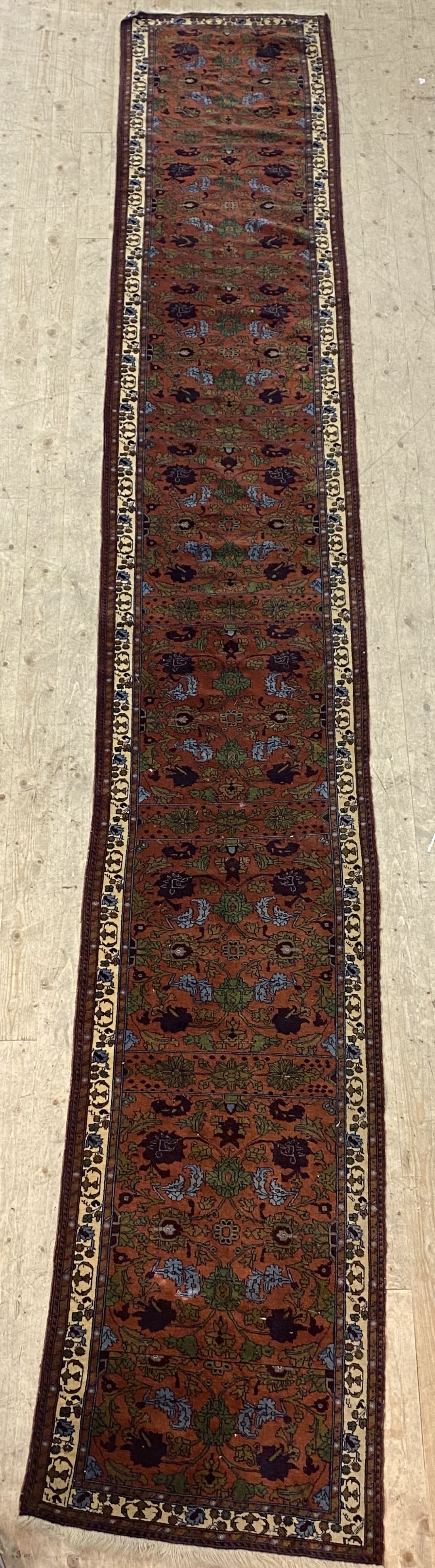 A Persian hand-knotted wool runner rug, mid-20th century, the dark red field having seven panels