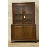 An Edwardian Arts and Crafts two part mahogany cabinet, with twin lead glazed doors opening to three