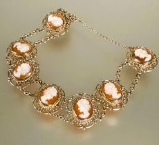 A 9ct gold bracelet set seven shell carved cameos in scrolling open work setting between chain