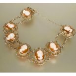 A 9ct gold bracelet set seven shell carved cameos in scrolling open work setting between chain