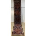 A long hand-knotted Persian Heriz runner rug, the busy blue field with five octagonal medallions,