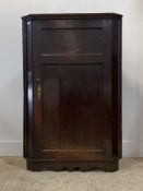 A George III oak corner cupboard, late 18th century, the twin panelled door enclosing three shelves,