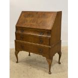 A 1930's walnut bureau with fall front opening to a fitted interior, above three drawers and