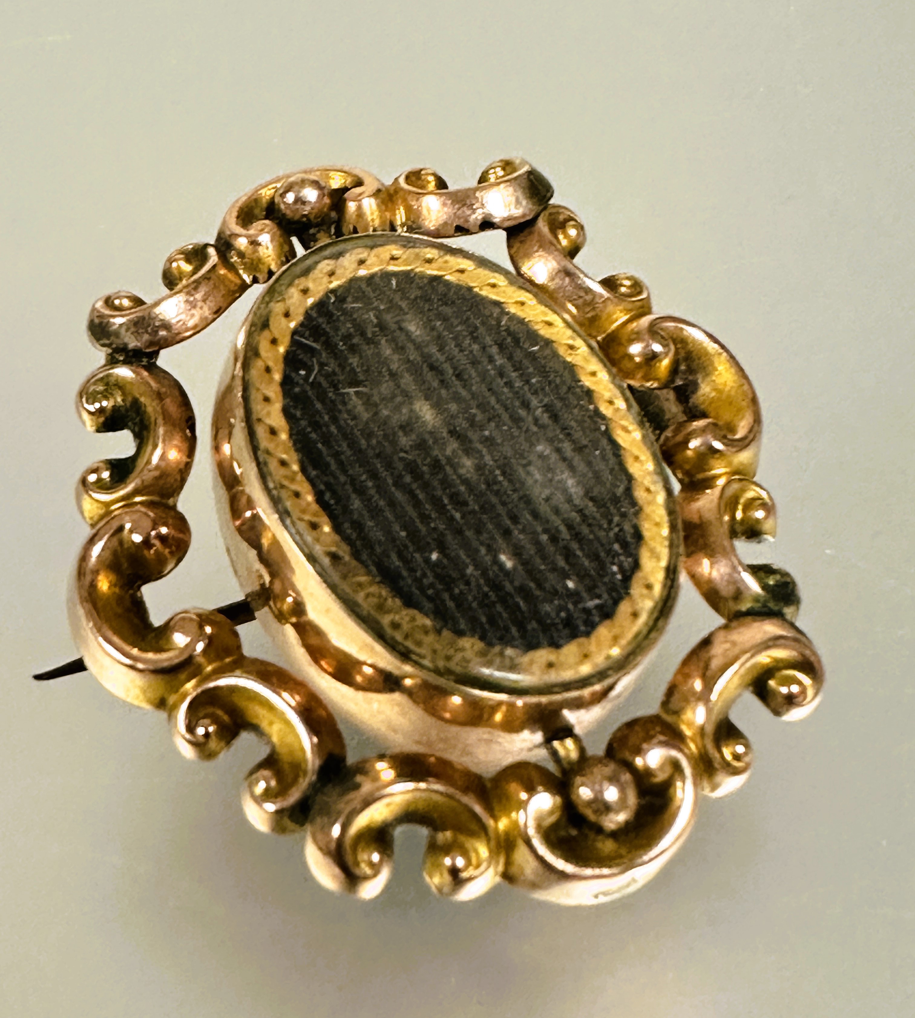 A Victorian yellow metal brooch with central revolving glazed oval panels enclosed within a rococo - Image 2 of 4