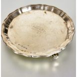 A Sheffield silver George III style card waiter with scalloped edge raised on three scroll feet with