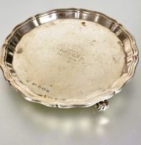 A Sheffield silver George III style card waiter with scalloped edge raised on three scroll feet with