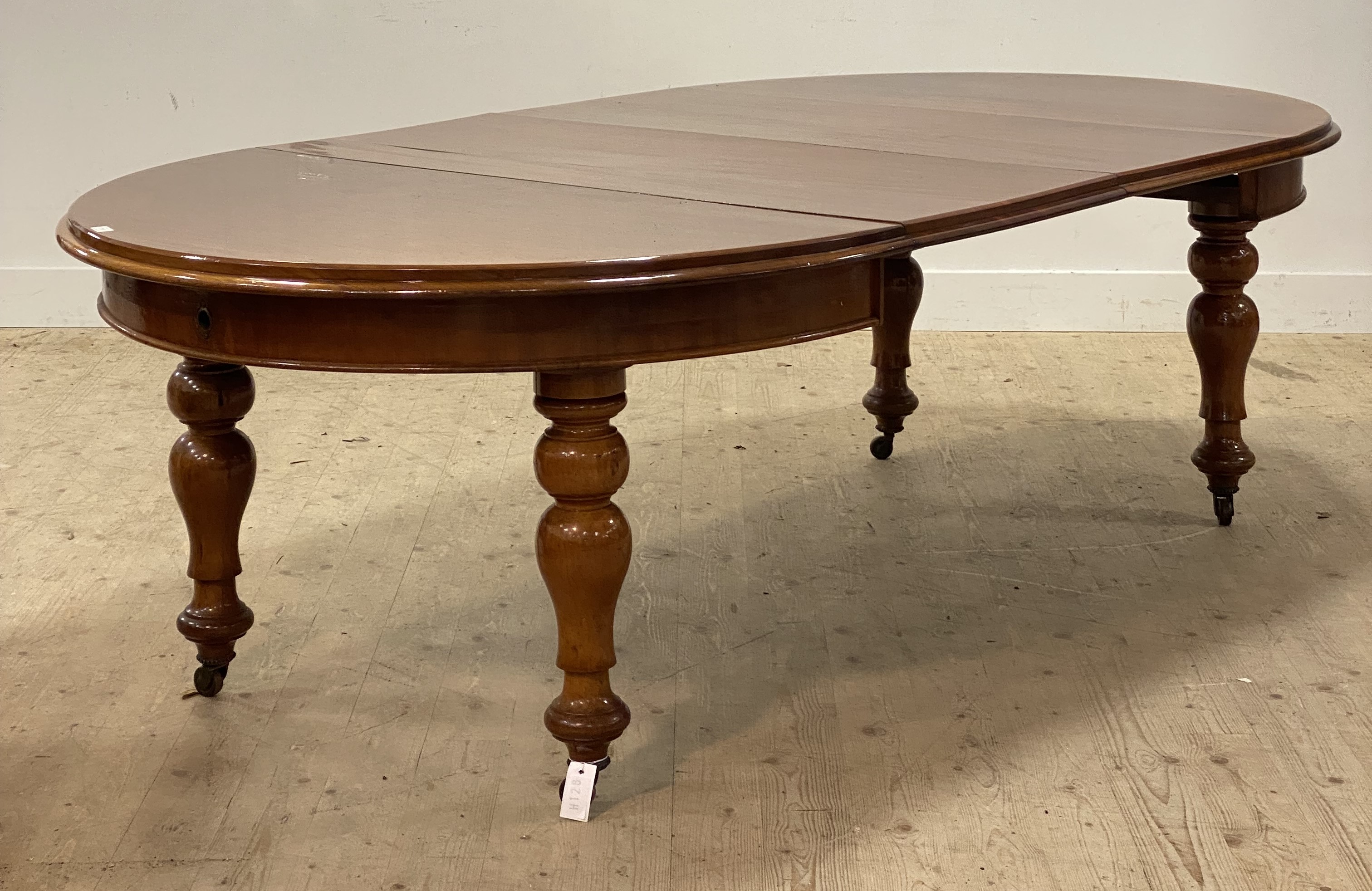 A Victorian mahogany wind out extending dining table, the oval top with two leaves, raised on turned