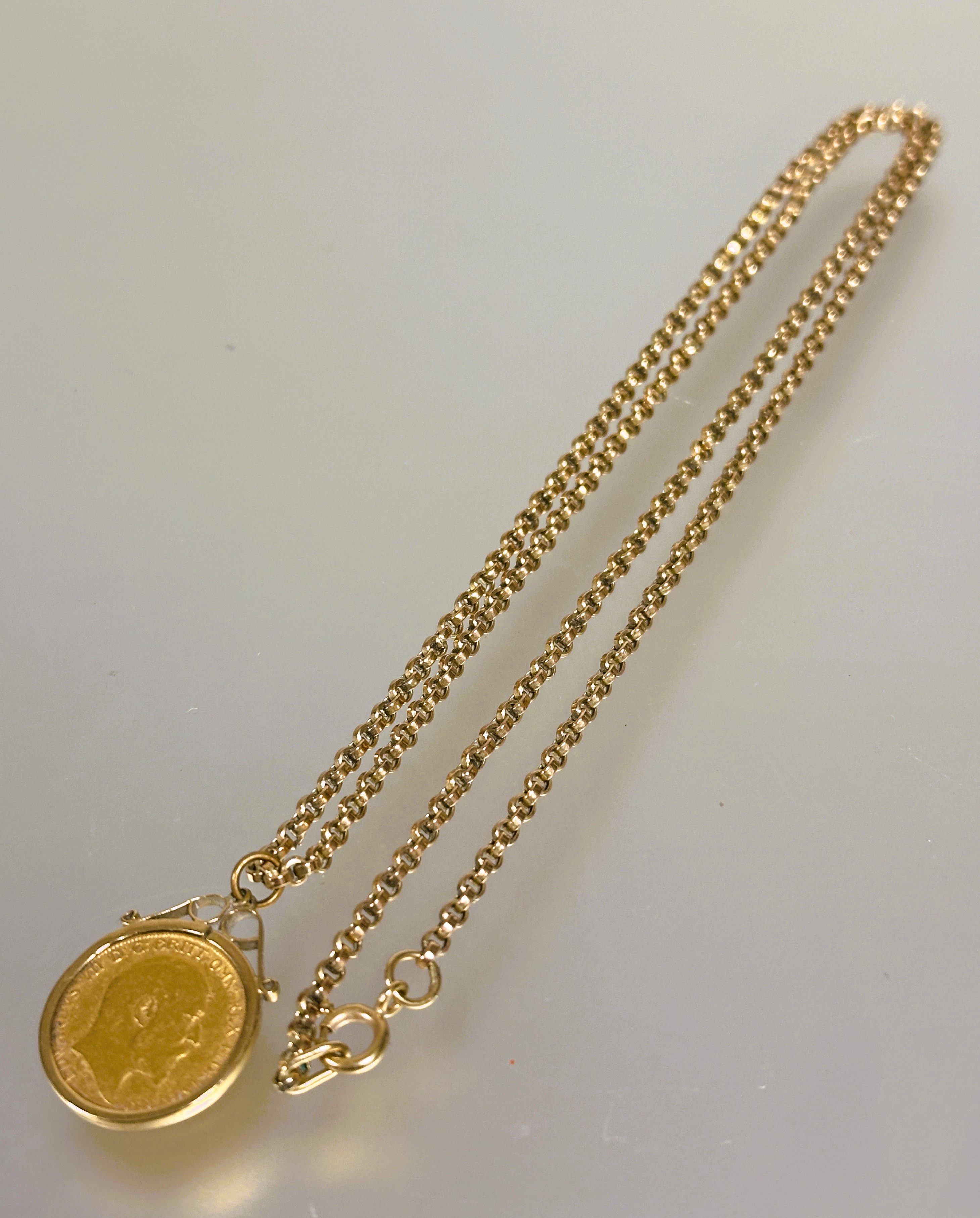 A Edward VII gold half sovereign 1902 in yellow metal frame on a 9ct gold belcher link chain