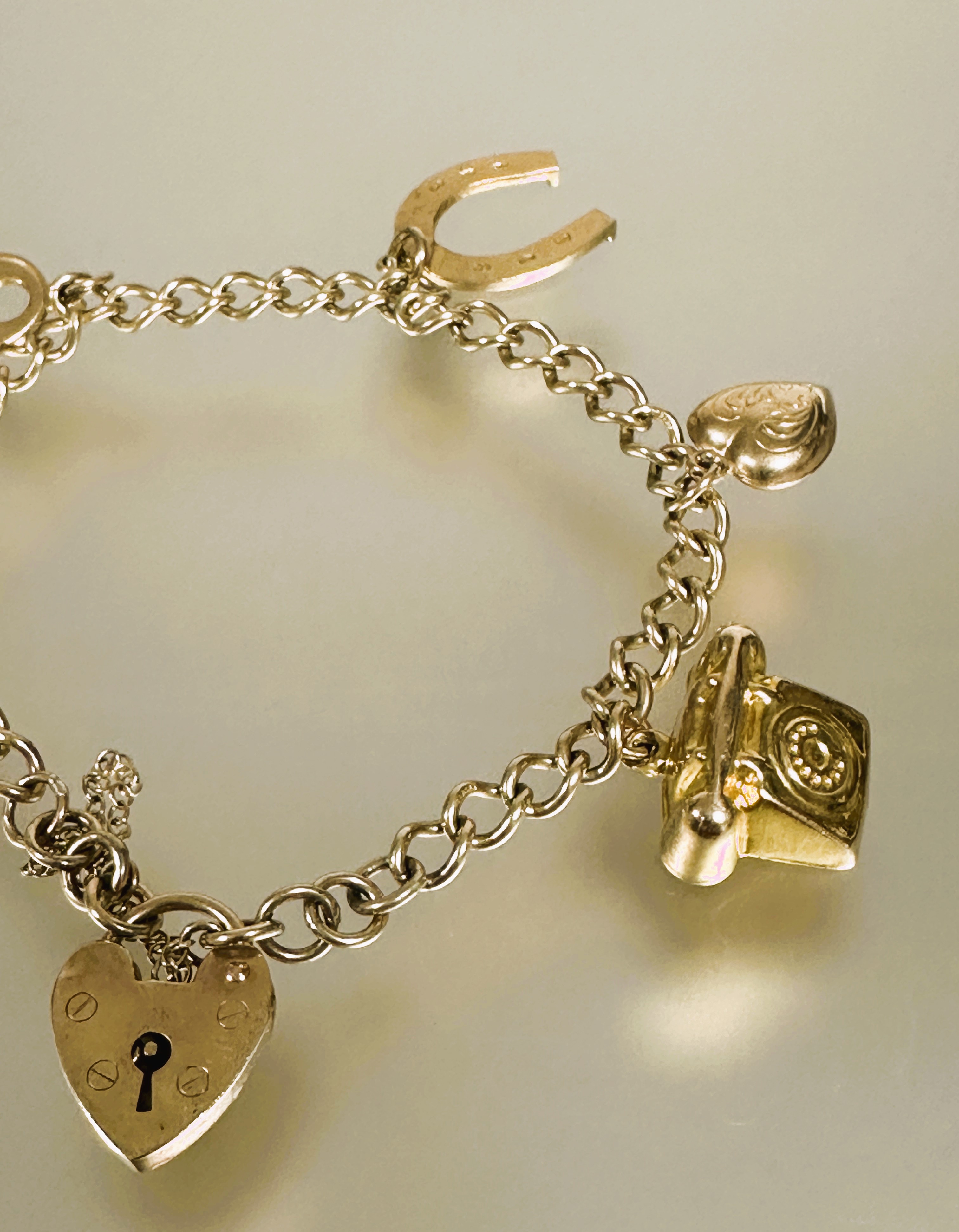 A 9ct gold kerblink bracelet with heart shaped padlock and safety chain and six various charms to - Image 3 of 3