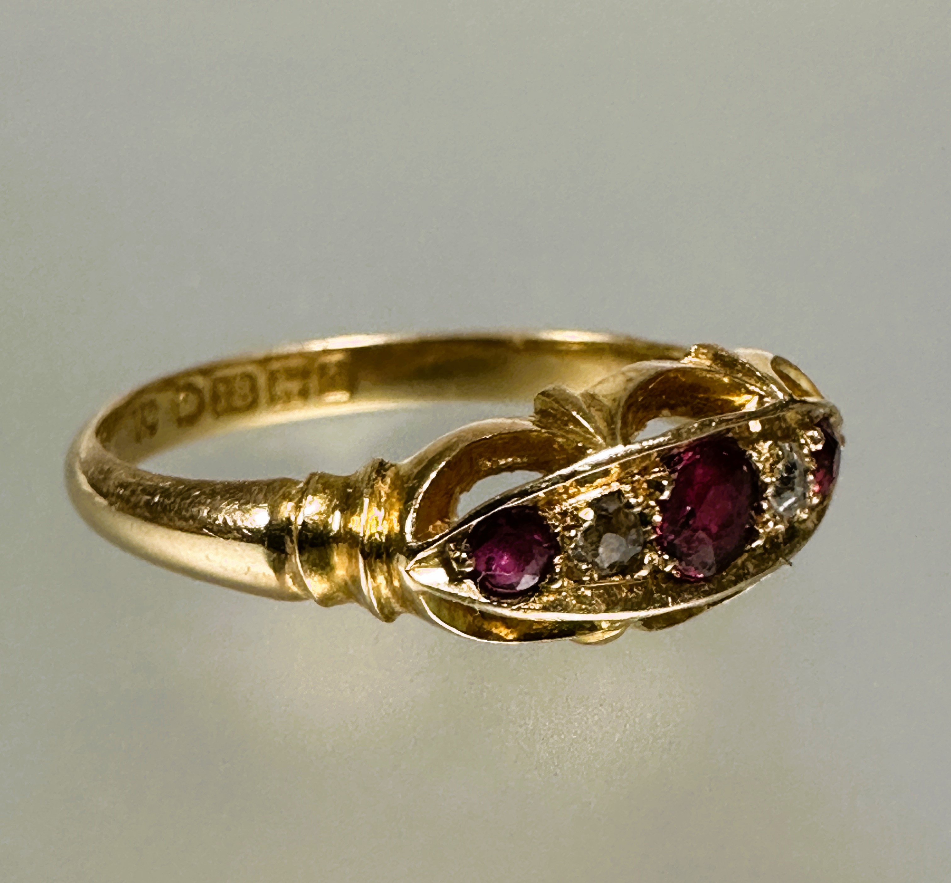 A 18ct gold three stony ruby ring the center cut stone 0.15ct flanked by a rose cut diamond and