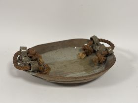 A large decorative stoneware pottery bowl with twisted hemp rope handles to side with green/brown