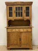 A Dutch pine two part dresser, the top section with bowed centre and four glazed doors, above a