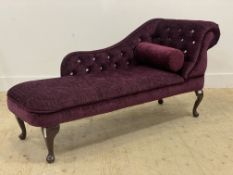 A small Victorian style chaise longue, the frame upholstered in plush plum buttoned fabric, raised