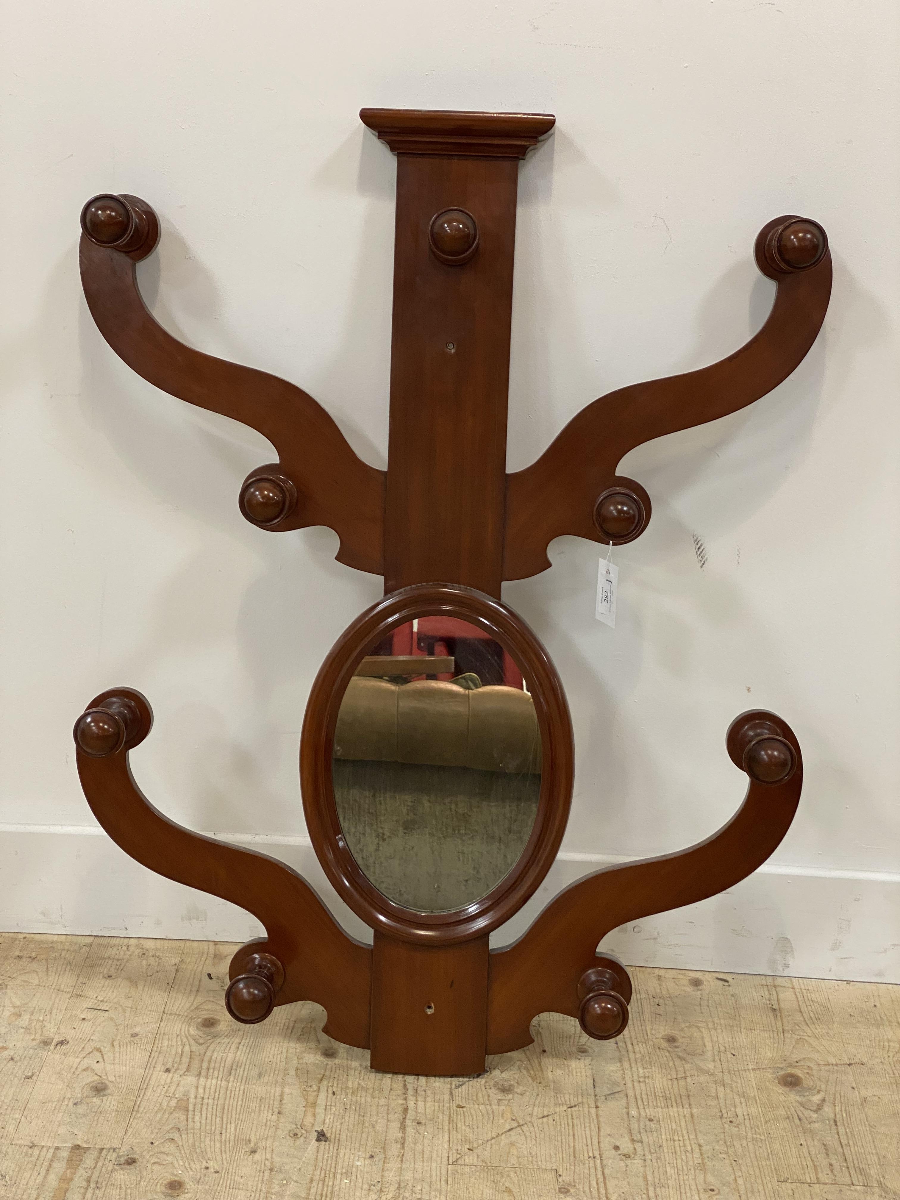 A Victorian mahogany wall mounted hat and coat stand with twin scrolling arms to each side and