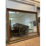 A large traditional gilt composition framed wall mirror with moulded frame enclosing bevelled glass.