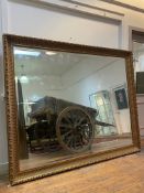 A large traditional gilt composition framed wall mirror with moulded frame enclosing bevelled glass.