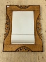 An early 20th century wall hanging mirror, the oak frame with beaded moulding and pierce carved with