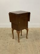 A mahogany veneered side table, the top with drop leaf to each end above a panelled door opening