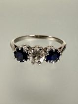 A platinum three stone sapphire and diamond ring, the central round brilliant cut diamond