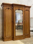 A Victorian mahogany breakfront triple wardrobe, the projecting cornice above a mirrored door to