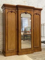 A Victorian mahogany breakfront triple wardrobe, the projecting cornice above a mirrored door to