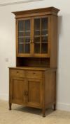 An Arts and Crafts period stained hardwood bookcase cabinet, the projecting cornice above two glazed