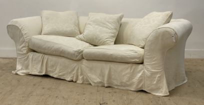 A large chesterfield sofa, with a loose fitted white cotton cover having embroidered floral