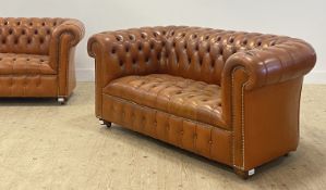A pair of Traditional chesterfield sofas, each upholstered in deep buttoned and studded tan leather,