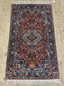 A Persian style silk and cotton blend rug, the central field profusely decorated with arabesques,