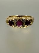 An 18ct gold three stone graduated ruby ring set two old cut diamond spacers flanking the centre