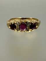 An 18ct gold three stone graduated ruby ring set two old cut diamond spacers flanking the centre