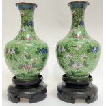 A pair of Chinese cloisonne vases typically decorated with floral motifs on a green ground with