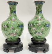 A pair of Chinese cloisonne vases typically decorated with floral motifs on a green ground with