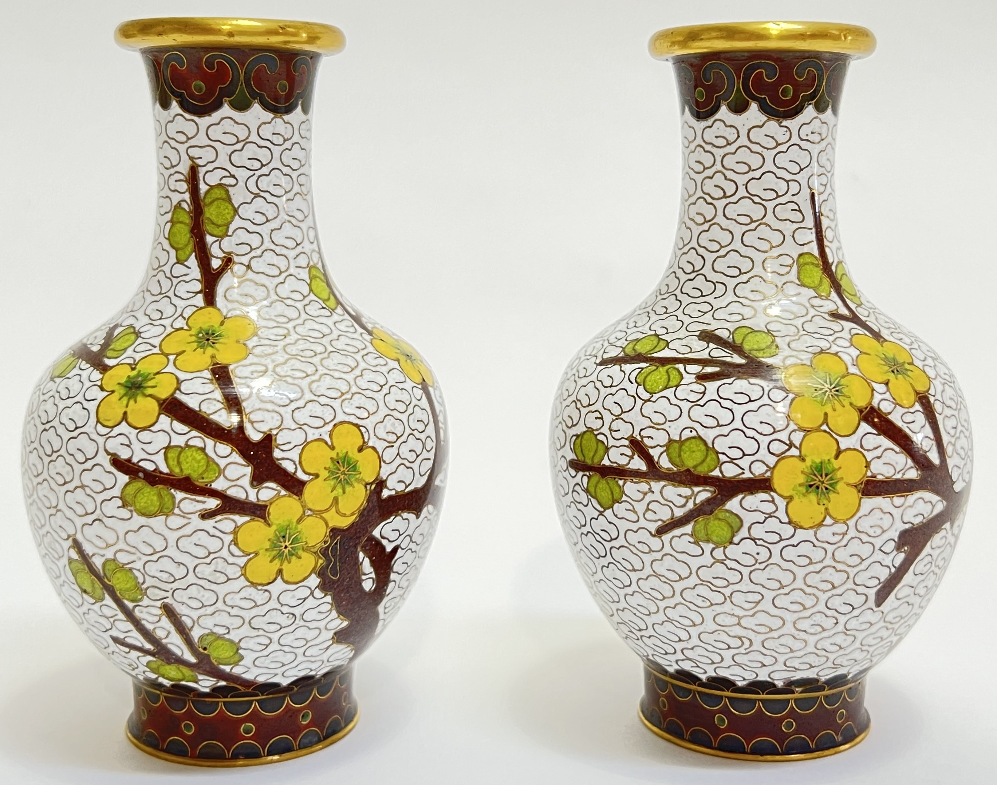 A pair of Chinese cloisonne enamel vases decorated with prunus blossoms against a white ground