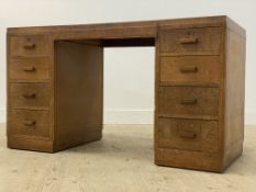 A 1930's oak knee hole desk, the top inset with skivered writing surface, above eight graduated