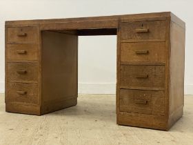 A 1930's oak knee hole desk, the top inset with skivered writing surface, above eight graduated