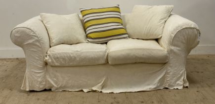 A chesterfield sofa, with a loose fitted white cotton cover having embroidered floral design,