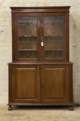 An Edwardian Arts and Crafts two part mahogany cabinet, with twin lead glazed doors opening to three