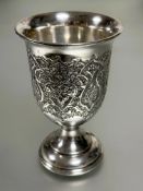 A Eastern white metal chased ceremonial chalice with repeating lotus leaf and flower design on