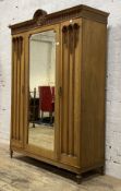An Edwardian oak wardrobe, the arched and fluted cornice centred with a low relief carved roundel,