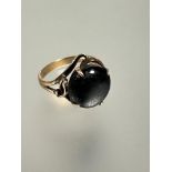 A 14ct gold ring of scrolling design with dark gray star sapphire, table rubbed, mounted in four