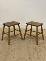A pair of vintage beech and elm stools, each with rectangular top raised on turned and tapered
