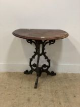 A Victorian style cast iron pub table, the demi lune mahogany top above three floral cast and