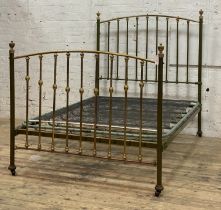 An Edwardian brass and green lacquered double bed frame, with urn finials, sprung base and moving on